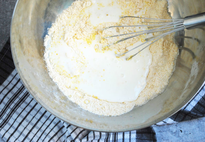 adding wet ingredients to cornmeal mixture in a bowl