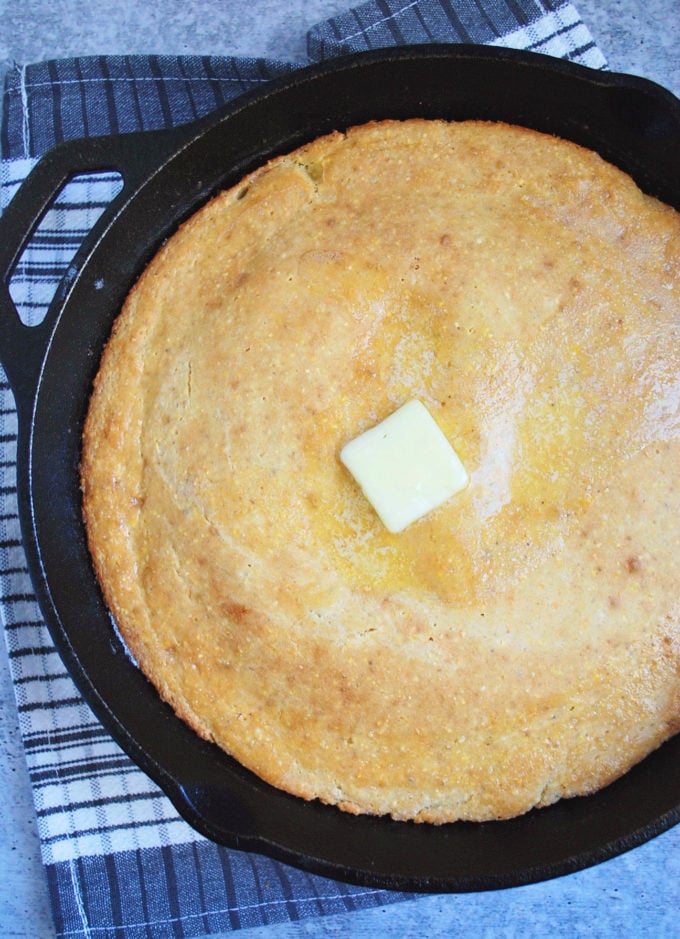 cornbread in a skillet with a pat of butter on top