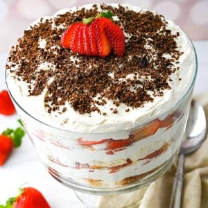 close up of a layered strawberry cheesecake trifle with grated chocolate and a fanned strawberry on top
