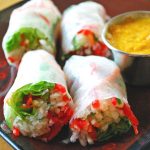 close up photo of two Vietnamese salad rolls on a plate with dipping sauce on the side