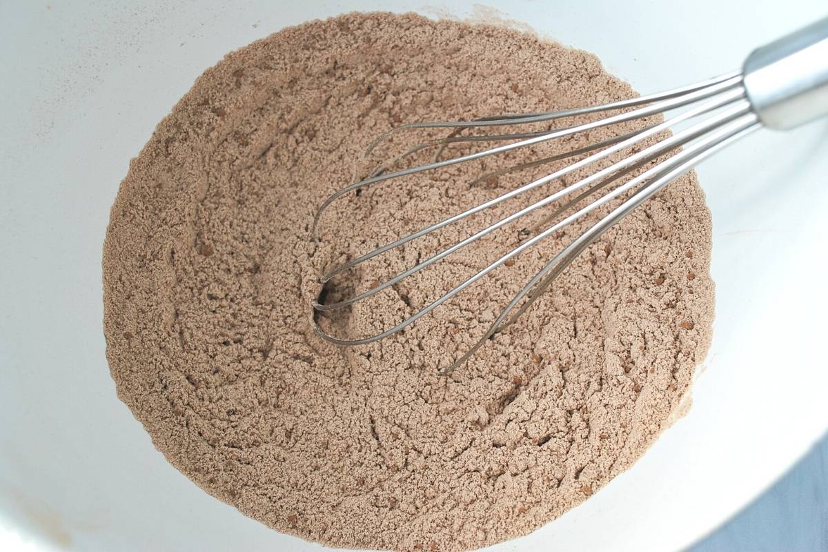 dry ingredients for protein brownies in a white bowl with a whisk