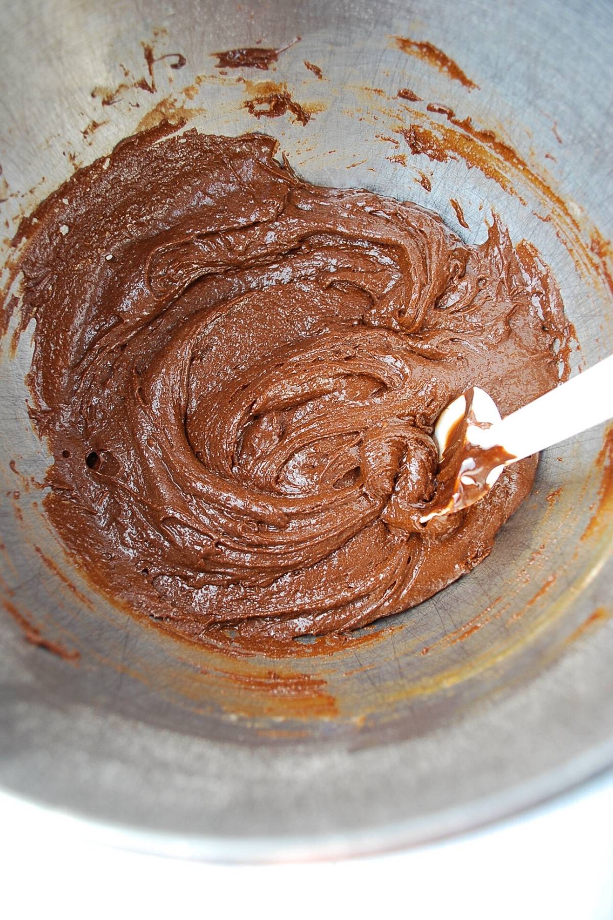 brownie batter mixed in a stainless steel bowl with a spatula