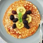 photo looking down on banana pancake with blackberries, kiwi, and fresh mint