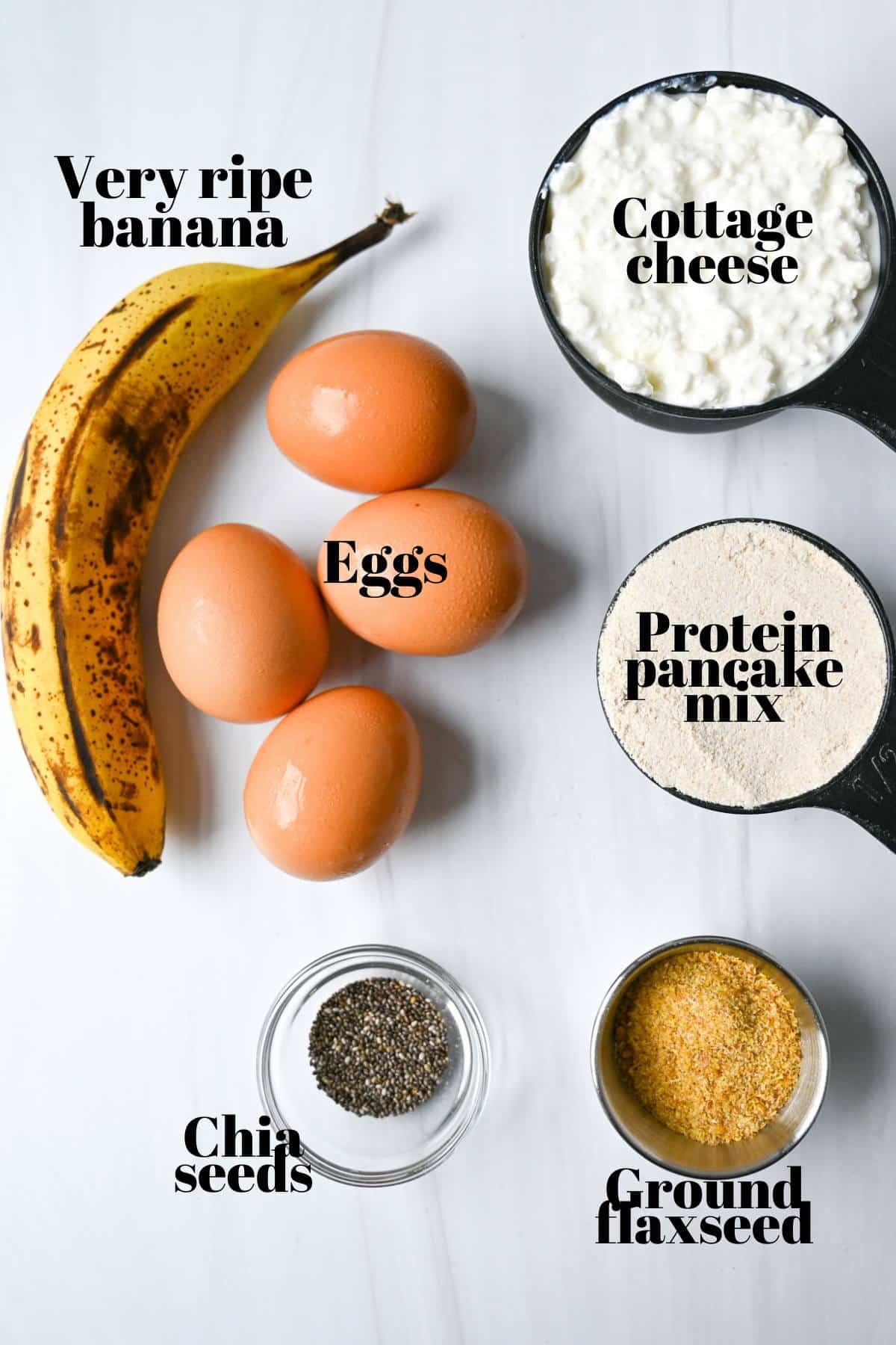 ingredients for making cottage cheese pancakes with ripe banana measured out on a counter and labeled