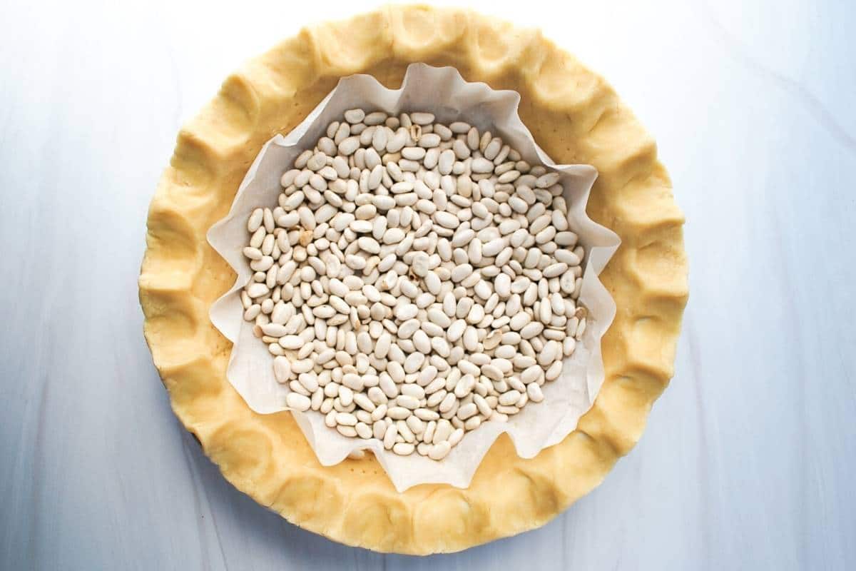 pie crust lined with parchment and dried beans ready to blind bake