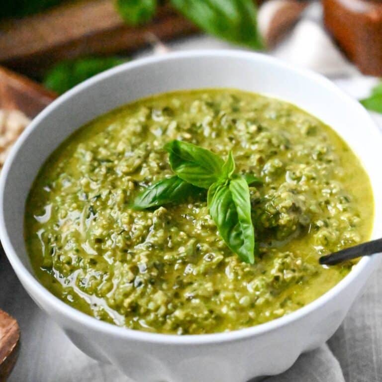 a bowl of pesto with fresh basil and a spoon