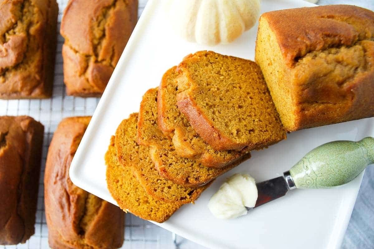 mini loaf of pumpkin bread sliced with a butter knife with butter