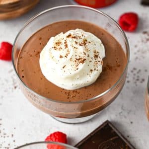 a dish of chocolate protein mousse topped with whipped cream and cocoa powder