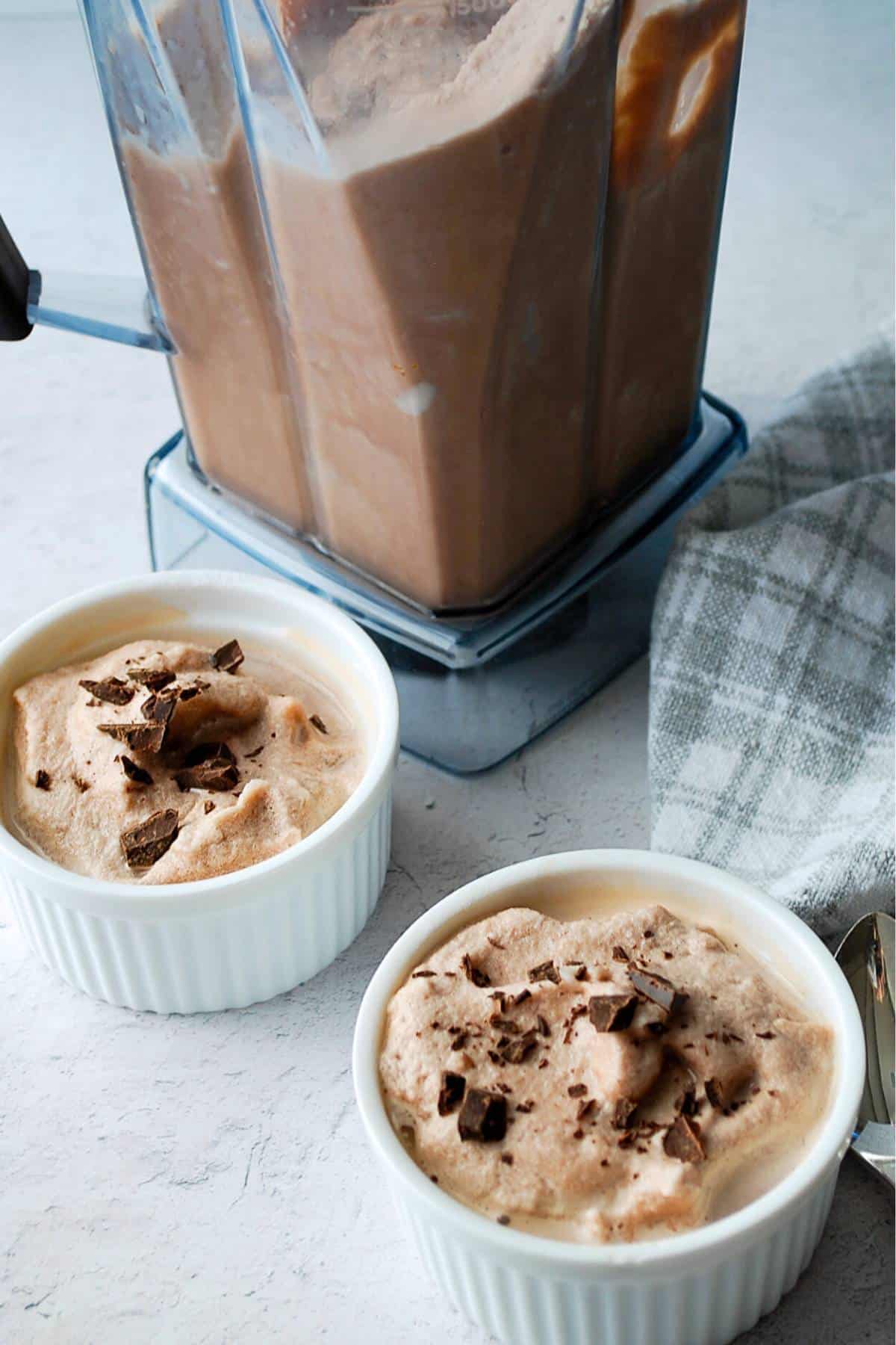a Vitamix blender jar with chocolate ice cream in it and two small dishes of ice cream next to it