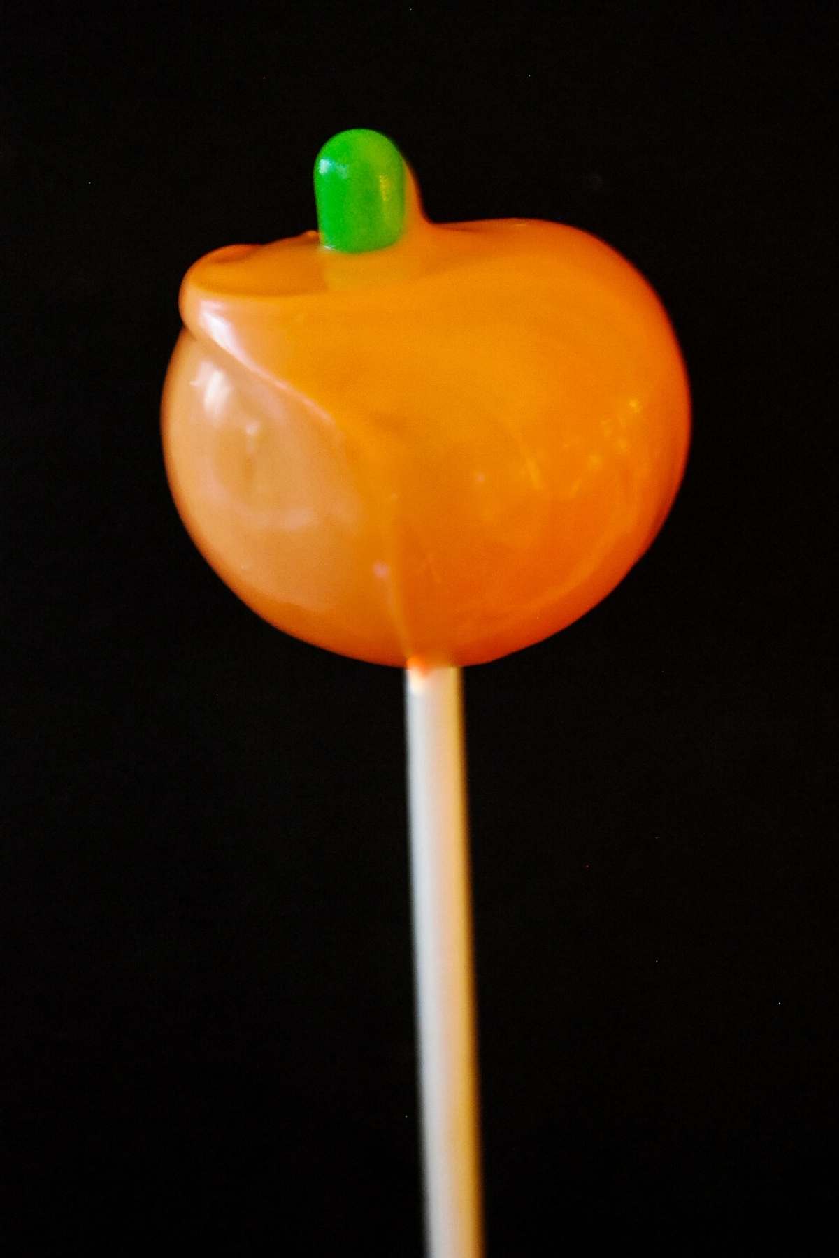 an orange pumpkin cake pop with a green tic tac for the stem