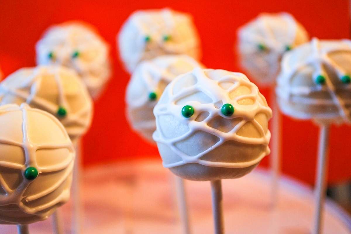 Mummy cake pops with green candy eyes with an orange background