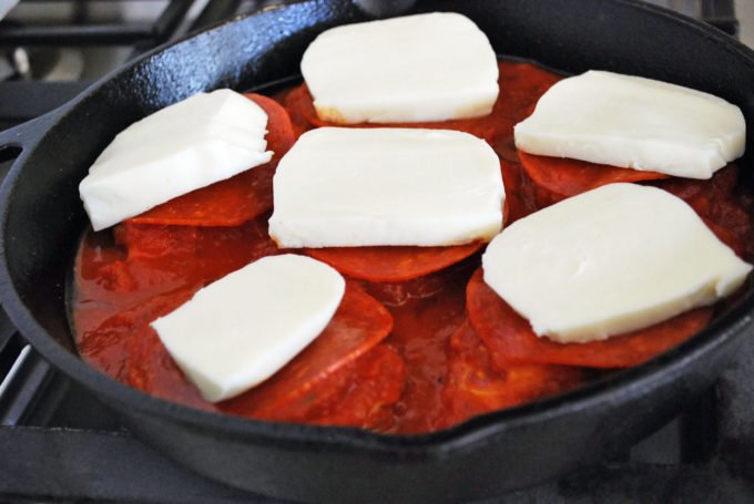 Sliced mozzarella on top of pepperoni and chicken breasts