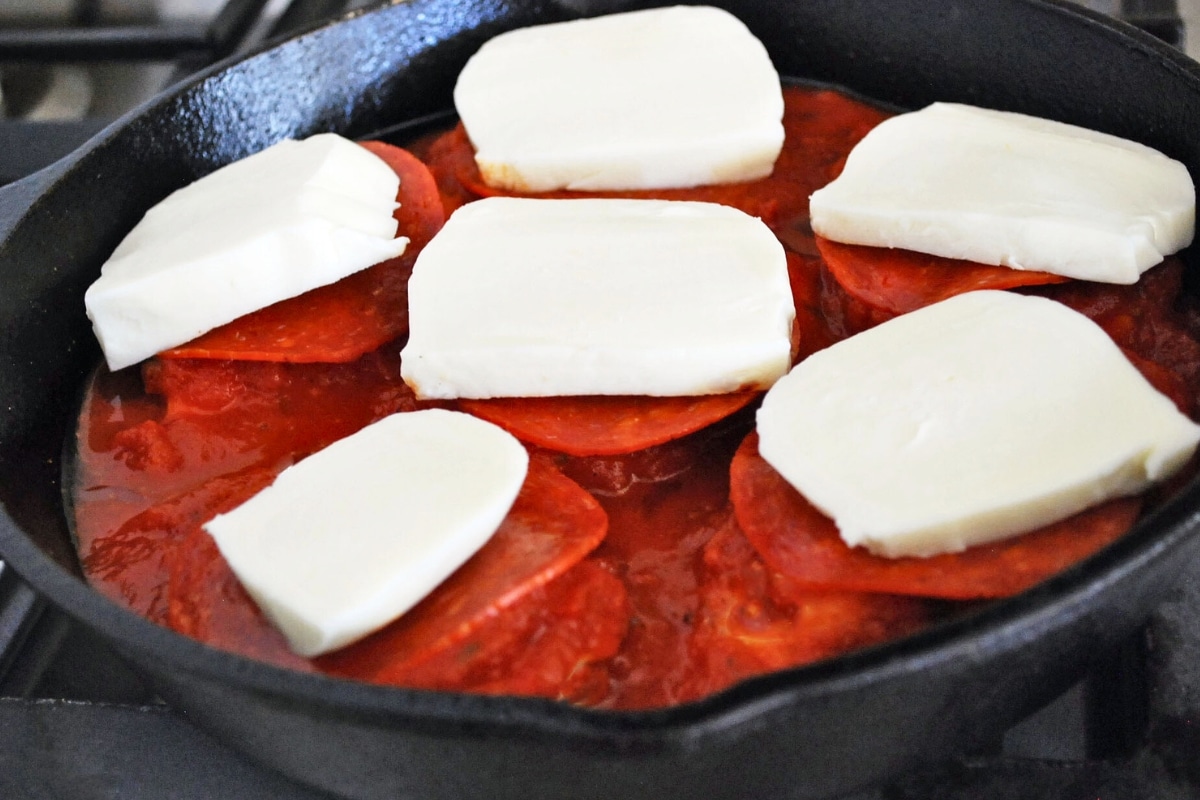 buffalo mozzarella on top of chicken breasts with pepperoni and sauce in a skillet