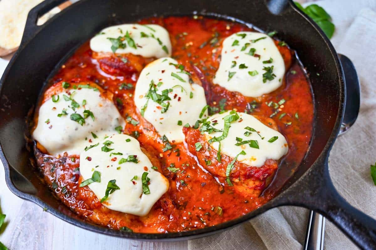 a baked pan of pizza chicken with basil