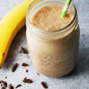 chocolate protein shake in a mason jar with green striped straw