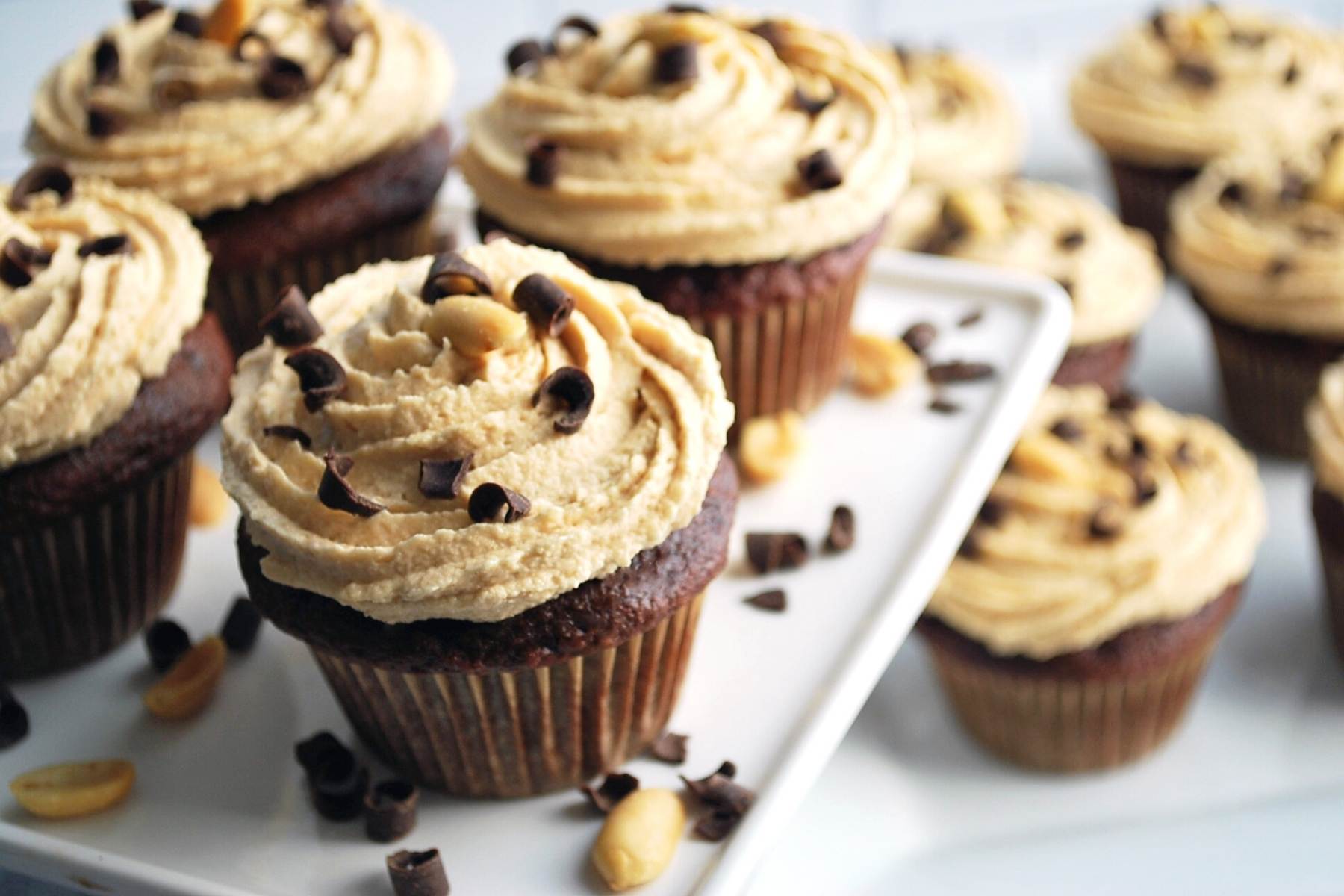 frosting cupcakes topped with a peanut and shaved chocolate