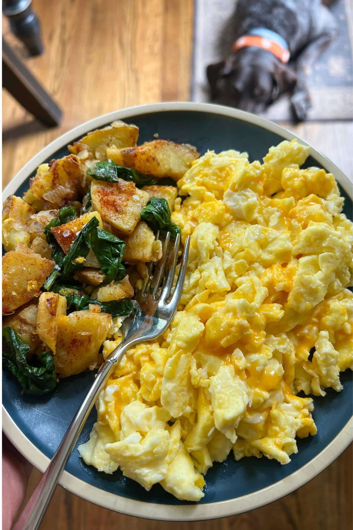  a plate of scrambled eggs with sauteed potatoes and wilted spinach