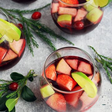 four glasses of red wine sangria garnished with lime