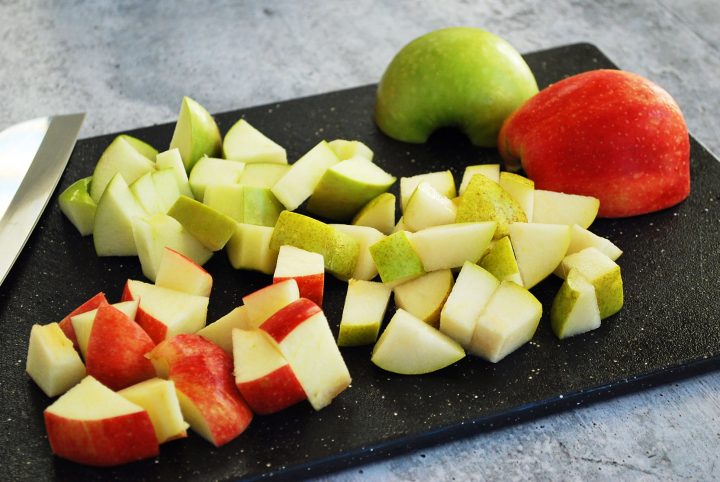 chopped pear and apples on a black cutting board