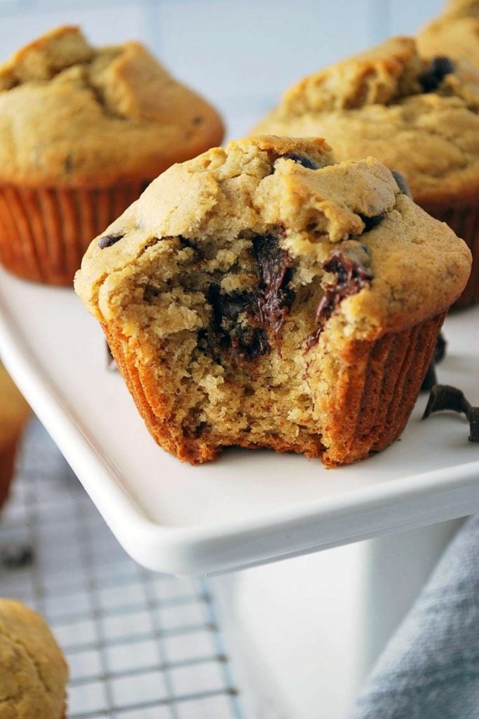 a banana chocolate chip muffin on a white platter with a bite out of it