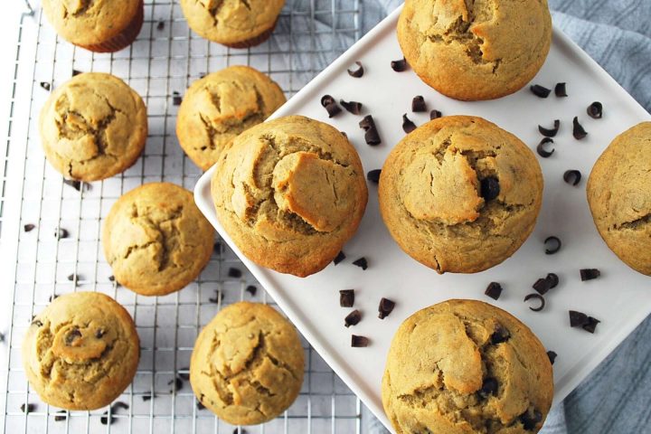 overhead photo of a platter of banana chocolate chip muffins and muffins on a rack with chocolate shavings