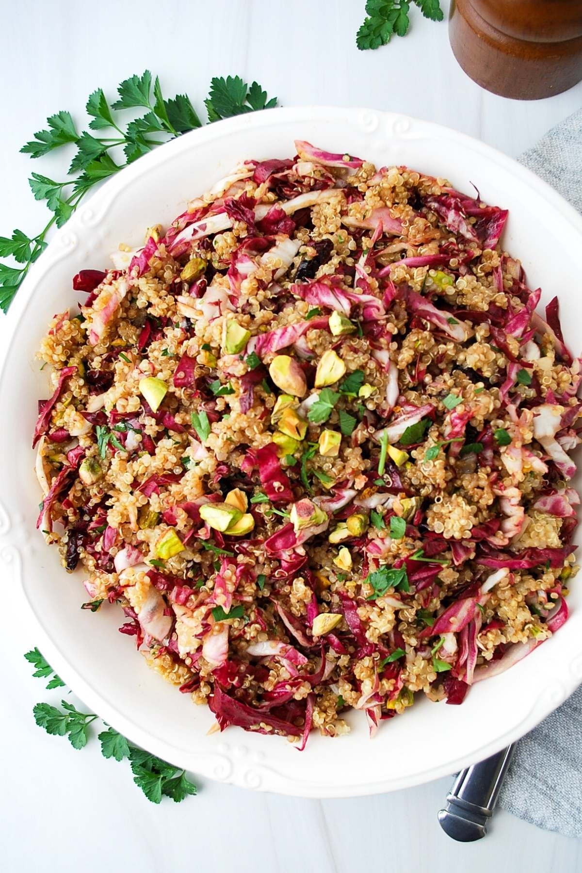 quinoa salad with cranberries in a serving bowl surrounded by fresh parsley