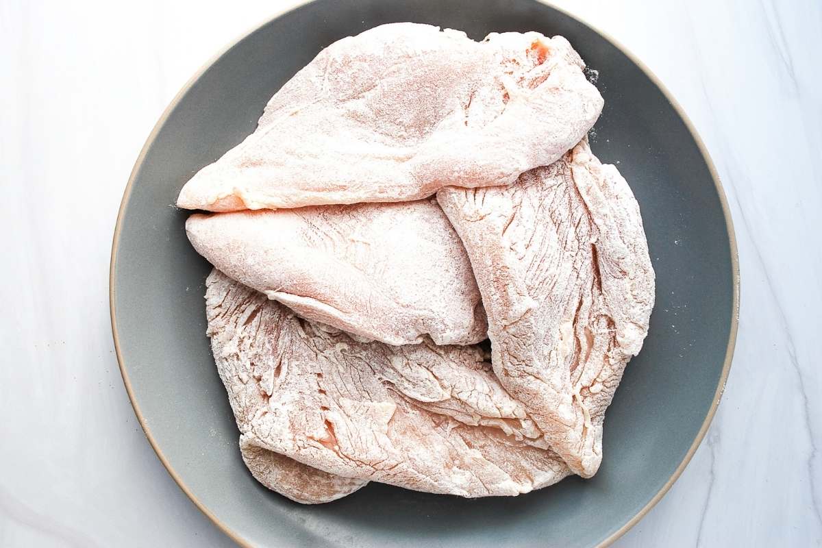 dredged chicken breasts on a plate