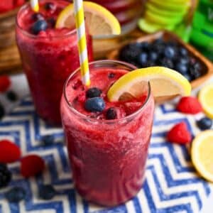 close up of two glasses of mixed berry sparkling mocktail with berries and a lemon slice on top
