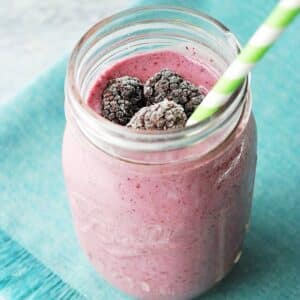 a creamy frozen berry protein shake with frozen blackberries on top