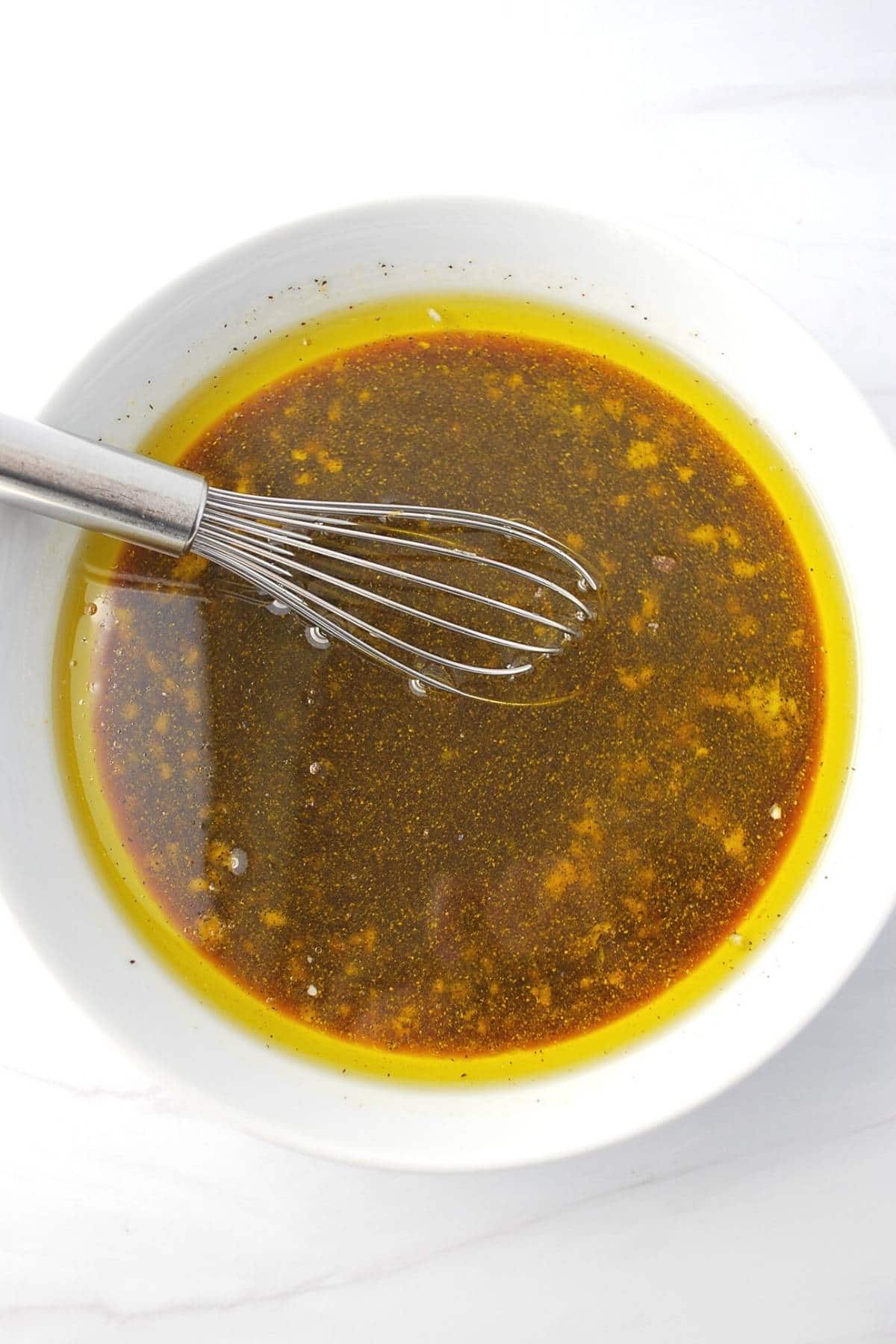 chicken marinade ingredients in a white bowl with a whisk