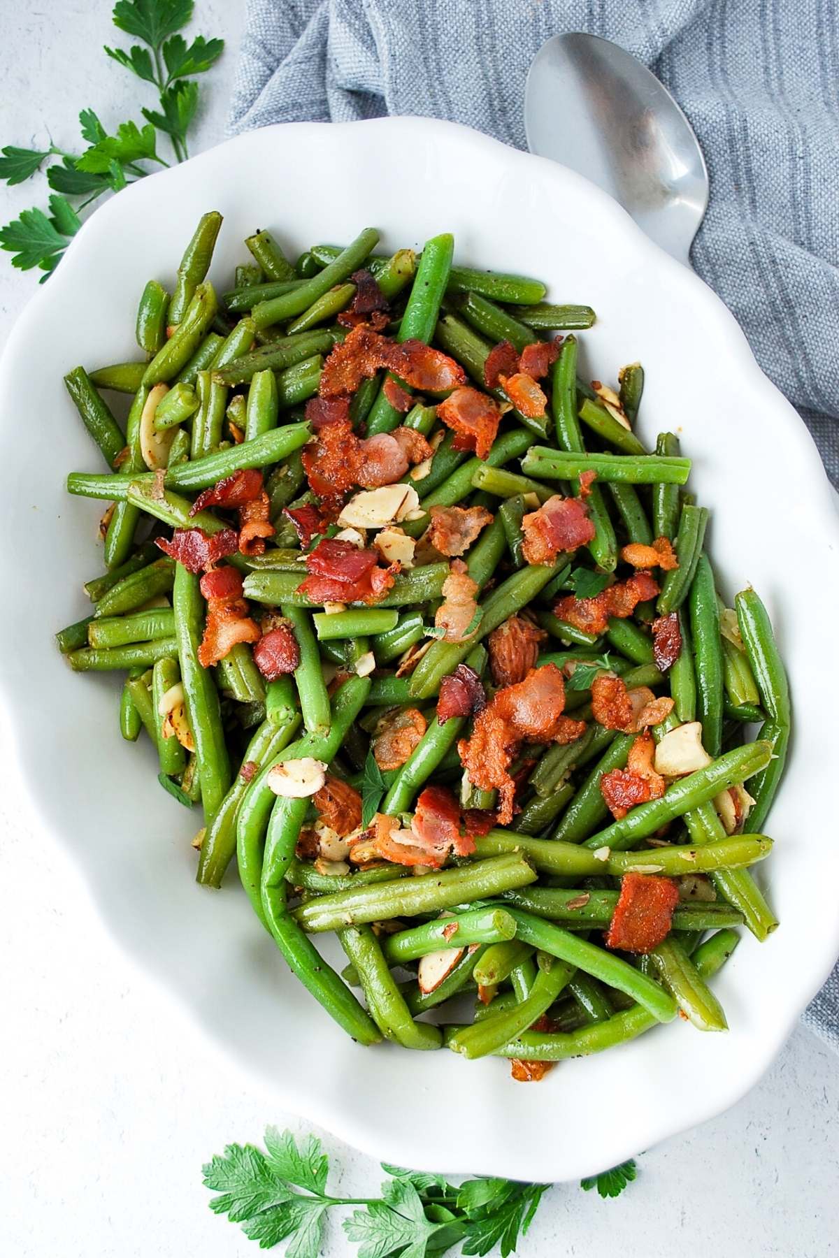 green beans almondine in a serving dish with fresh parsley