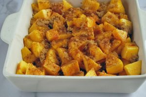 Fresh peaches tossed with sugar and spices in a baking dish