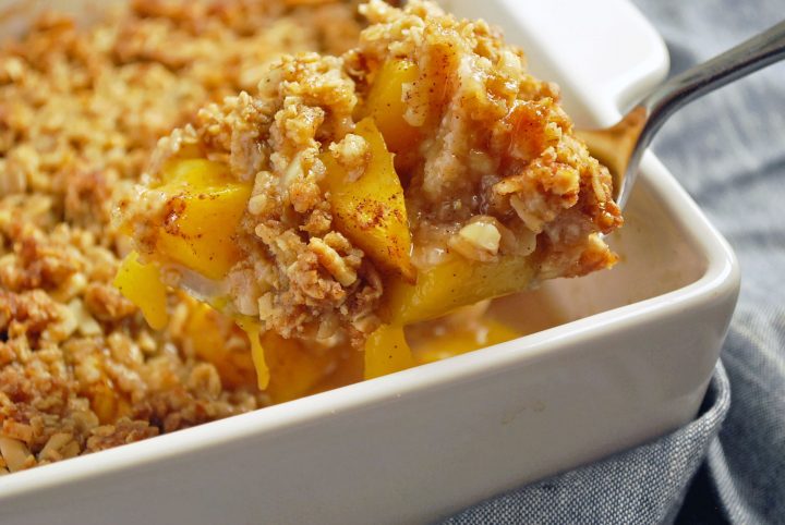 A serving of peach crisp with the pan in the background