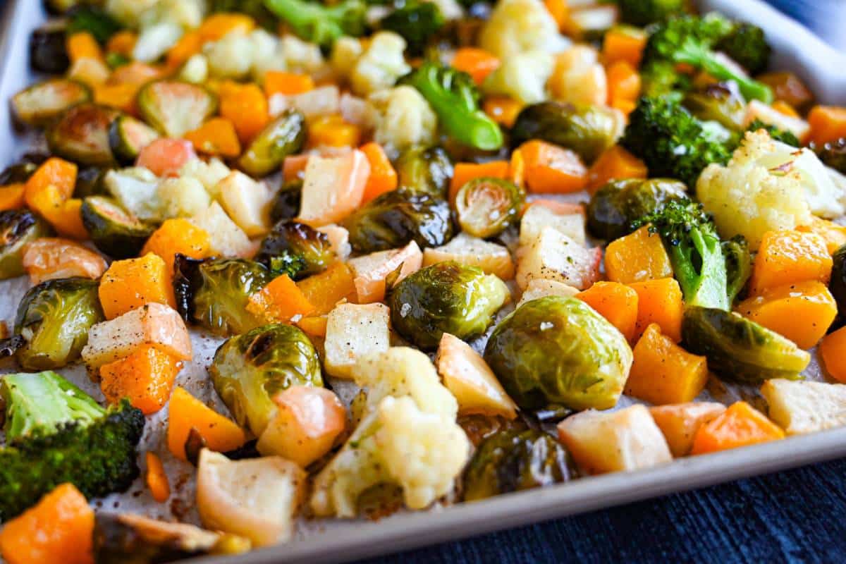 side view of a roasting pan with a medley of cooked fall vegetables and apples