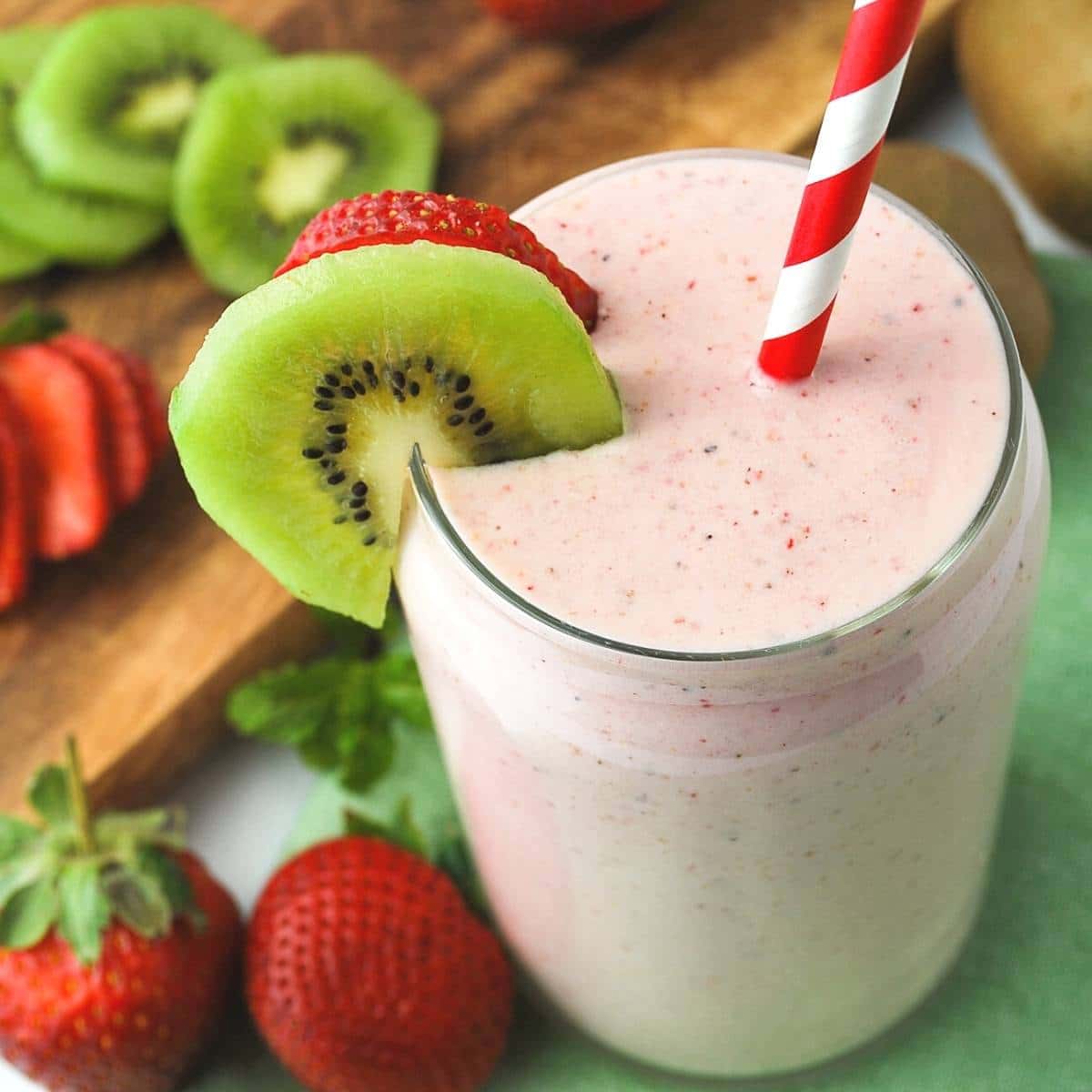 close up of a strawberry smoothie surrounded by sliced strawberries and kiwi