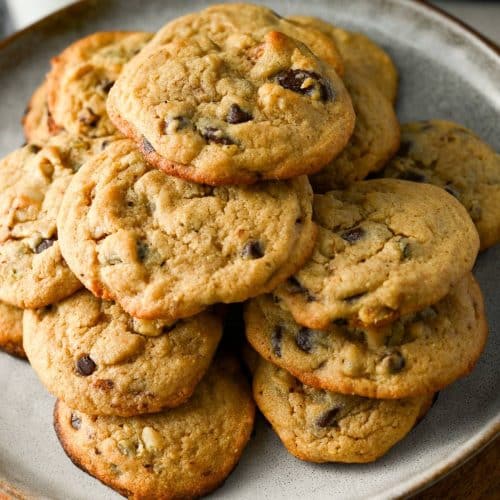 a plate full of stacked chocolate chip cookies