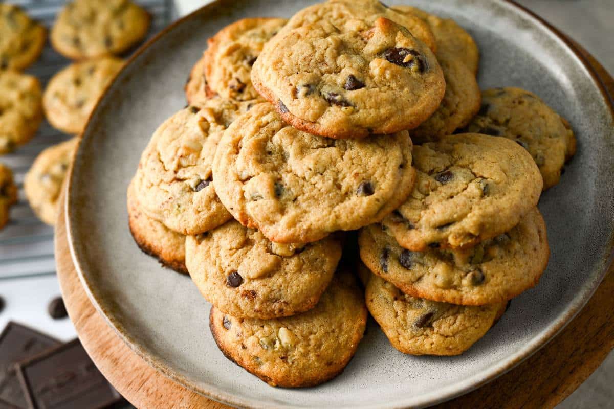 a platter of chocolate chip cookies with a rack of cookies underneath