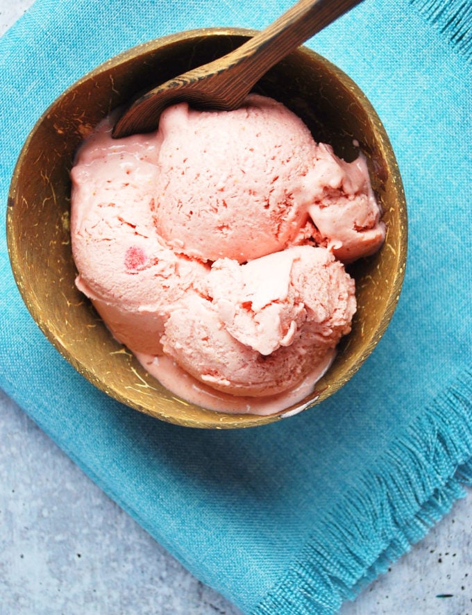 Overhead photo of strawberry frozen fruit ice cream in a coconut bowl 