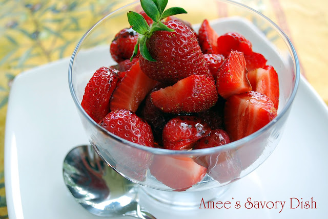 A bowl of marinated fresh strawberries with a spoon