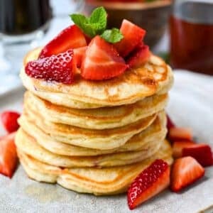 a stack of strawberry protein pancakes on a plate with fresh berries