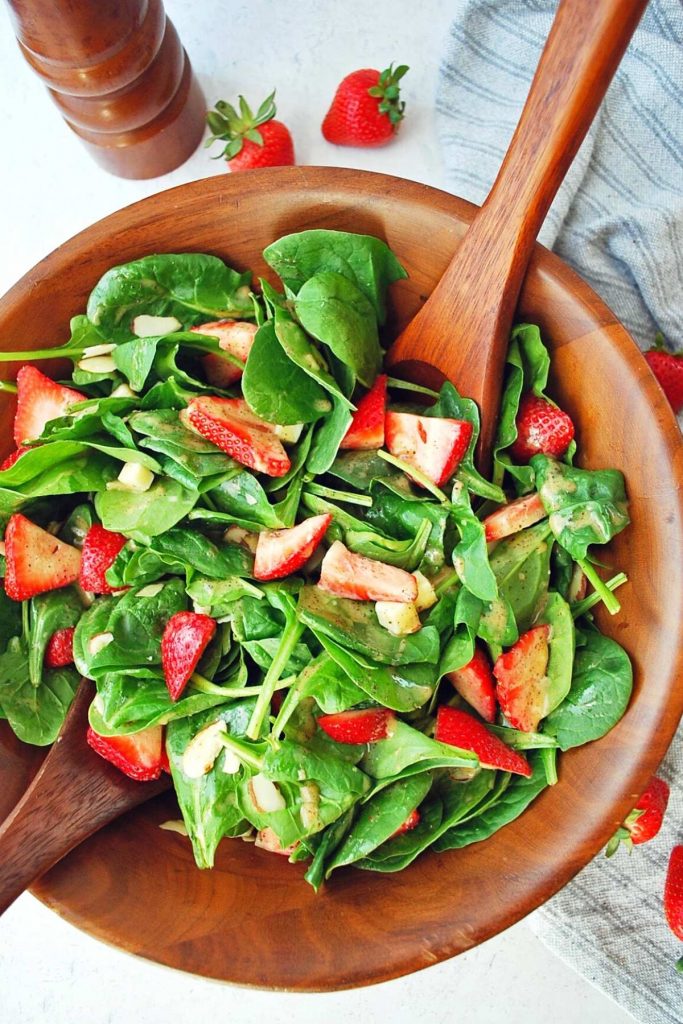 bowl of strawberry spinach salad with peppermill in the background