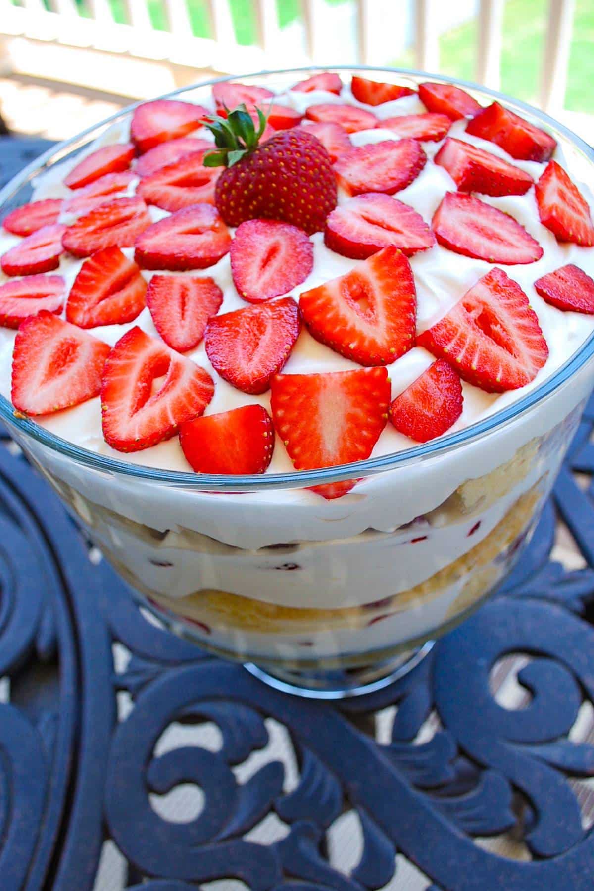 a strawberry trifle made with tres leche cake in a bowl on an outside table