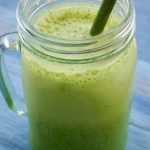 close up of a green smoothie in a glass with a green straw