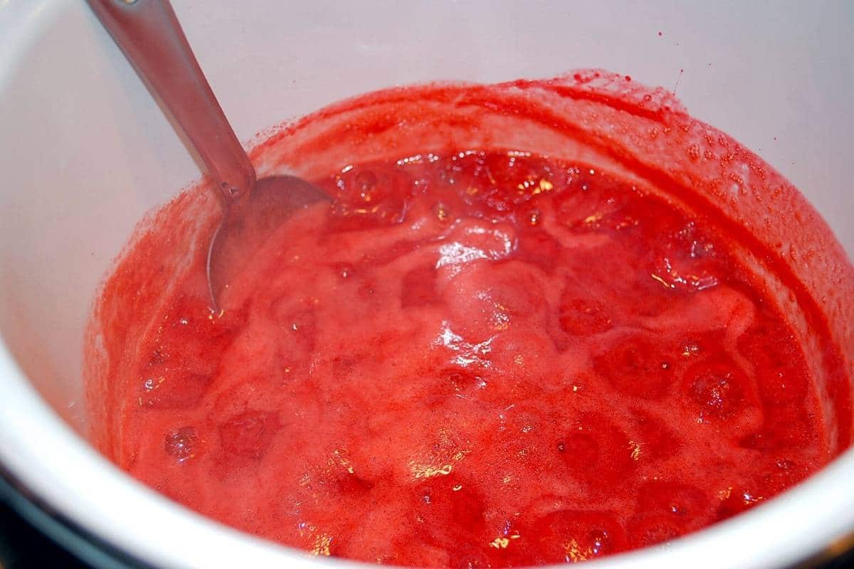 cooked low sugar strawberry jam in a bowl with a spoon