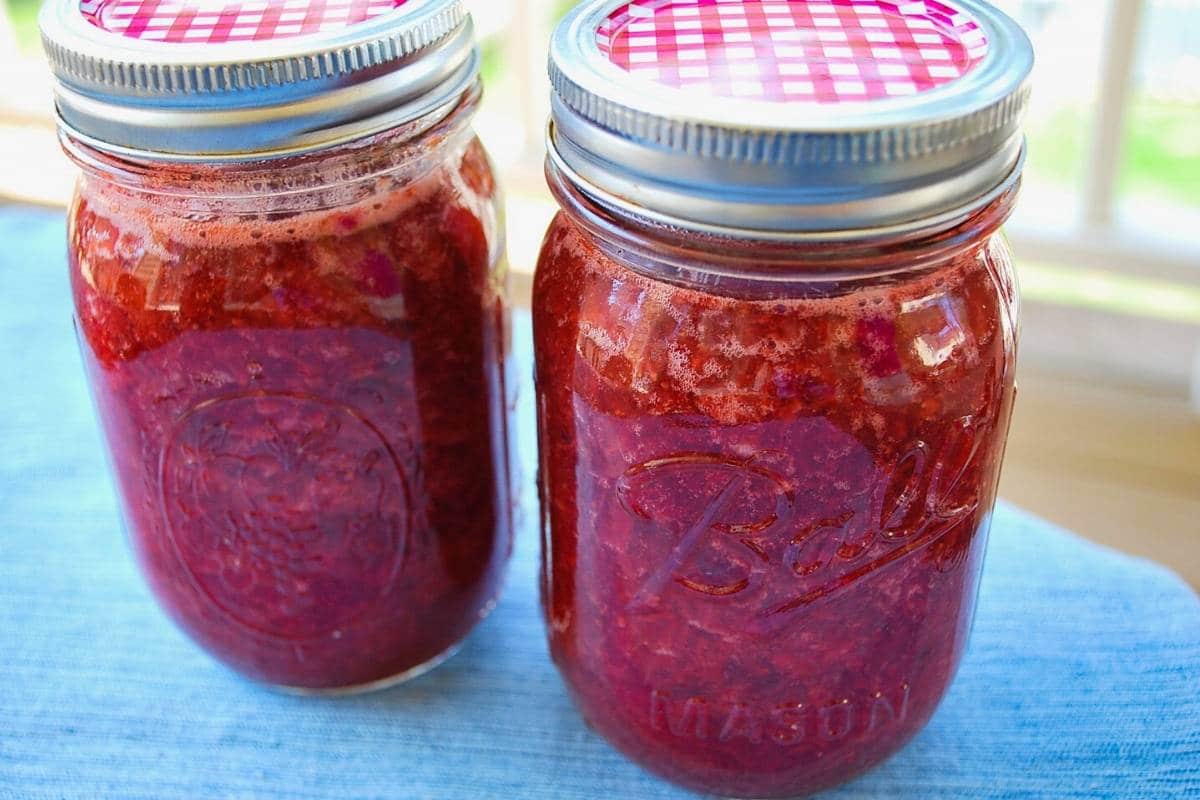 freshly made low sugar strawberry jam in two mason jars with lids