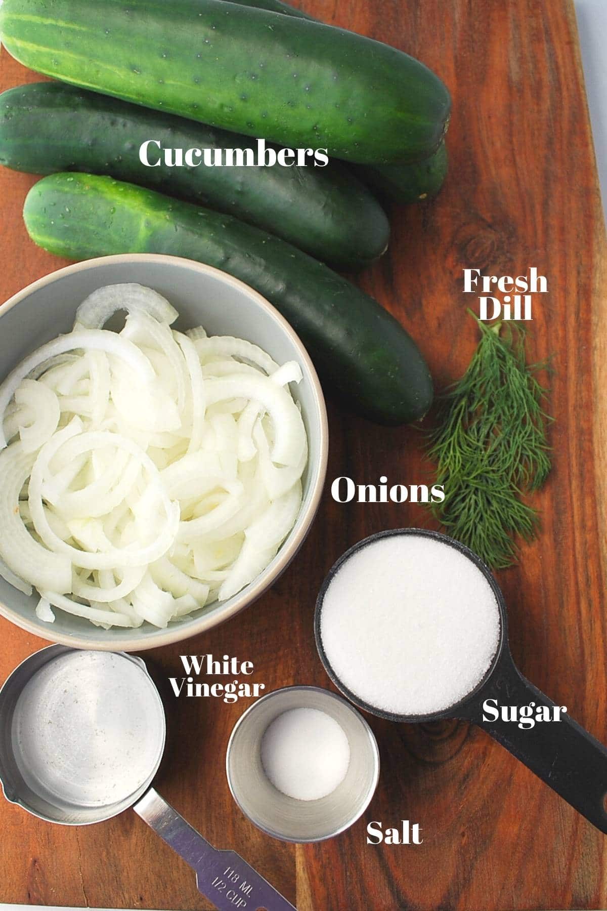 ingredients for cucumber salad on a wood cutting board
