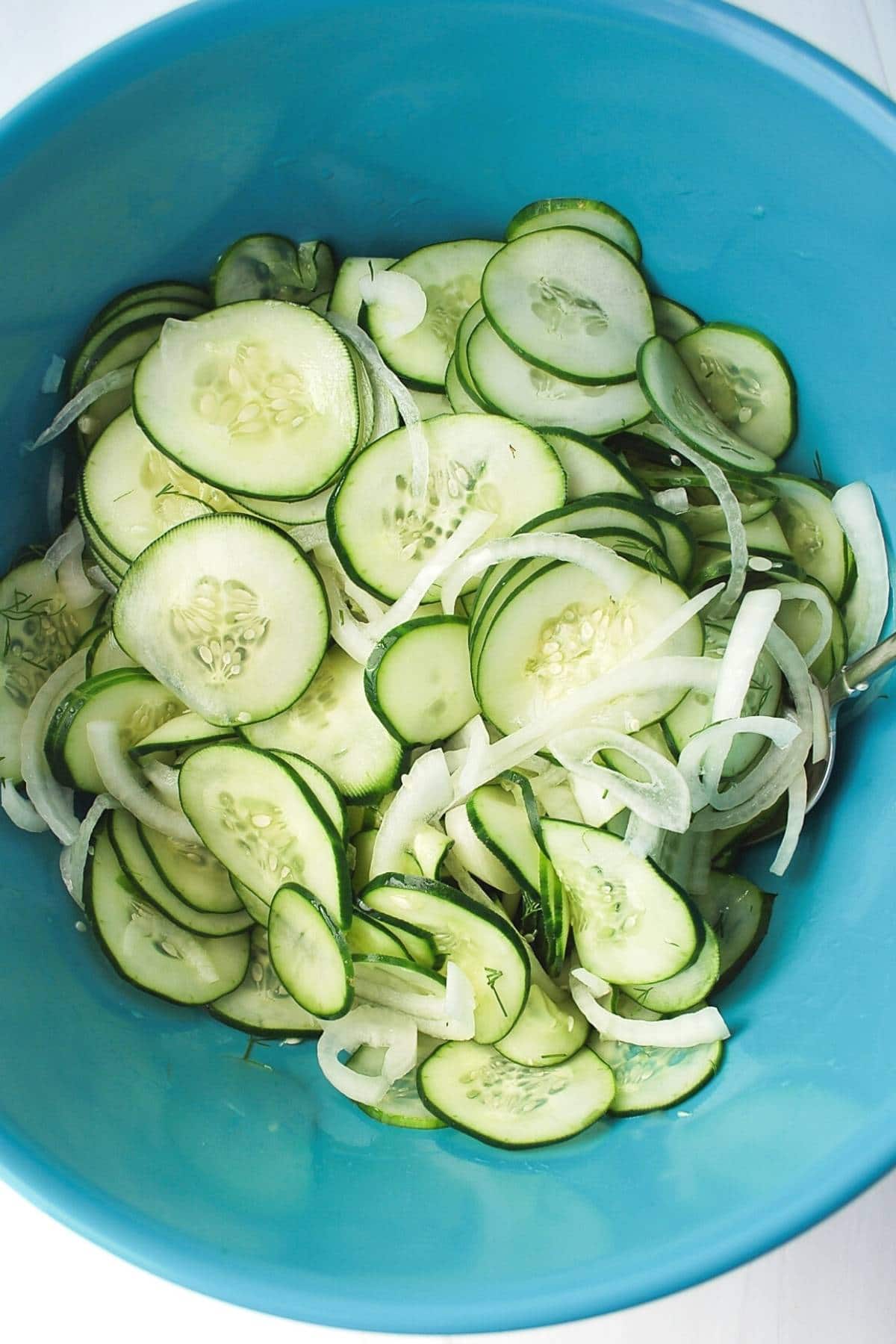 cucumbers and onions in a blue bowl ready to refrigerate