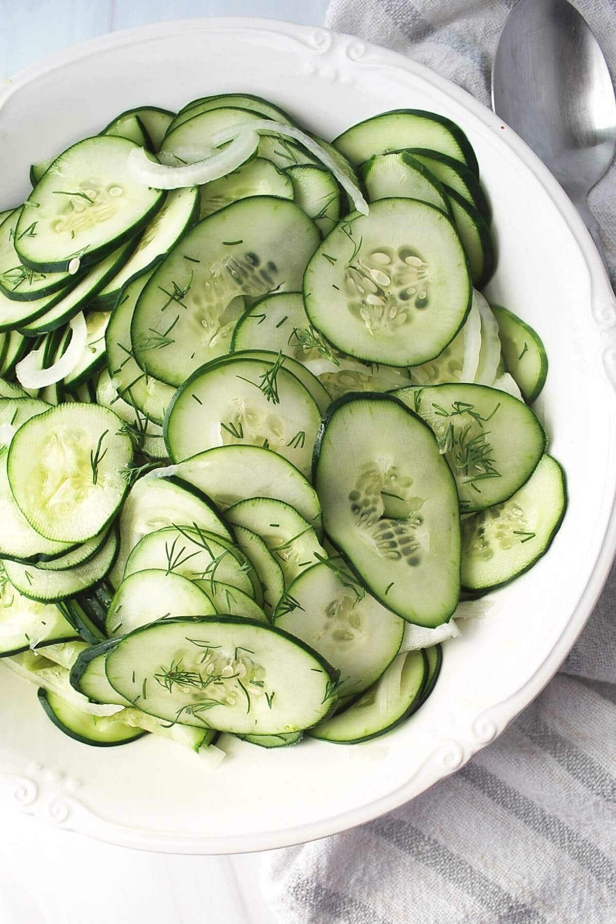 bowl of cucumbers and onions with a white tea towel underneath