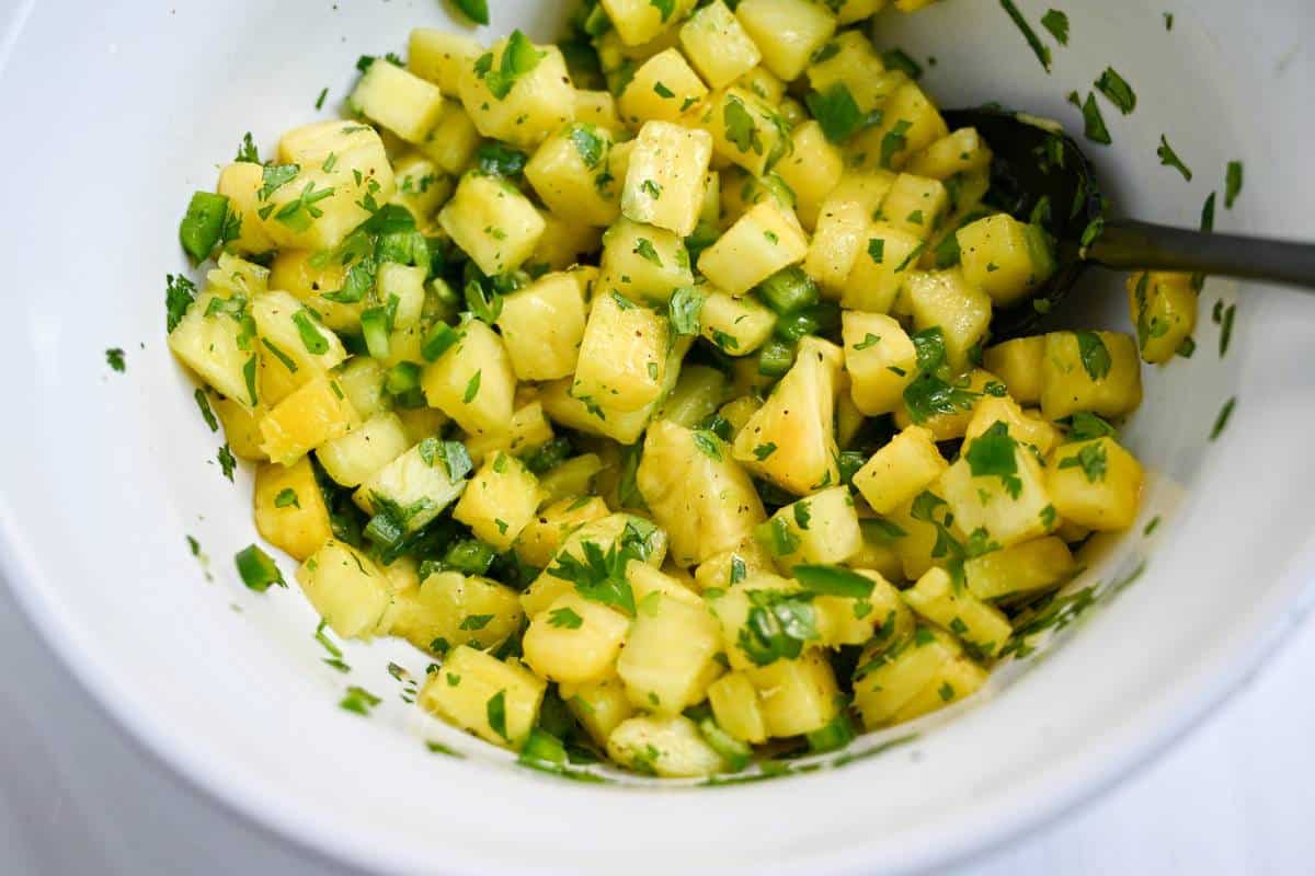 jalapeno pineapple salsa mixed in a white bowl with a spoon