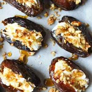 close up photo of stuffed dates on parchment paper drizzled with maple syrup